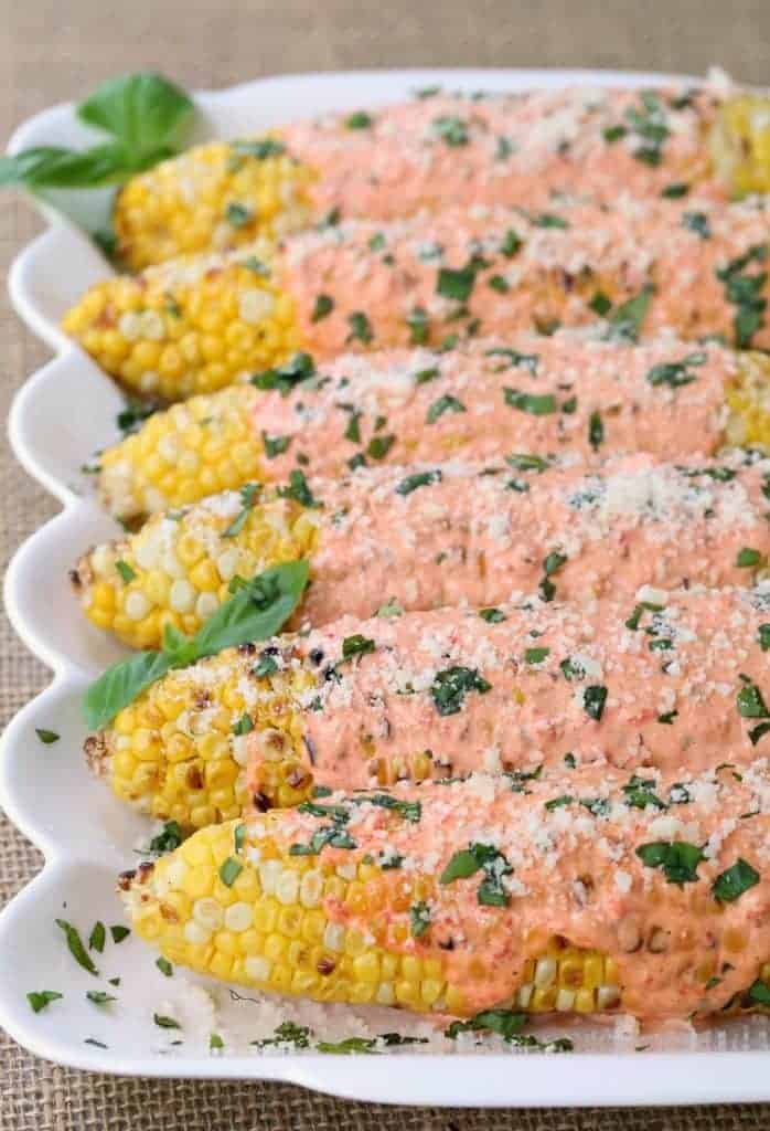 Grilled Italian Street Corn covered with red pepper mayo, cheese and basil!