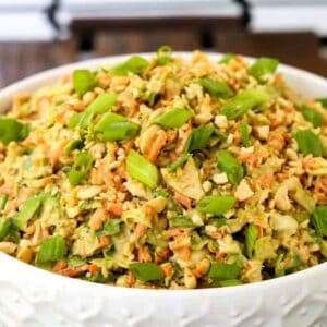 Thai Peanut Brussels Sprout Coleslaw in a white bowl on a serving tray