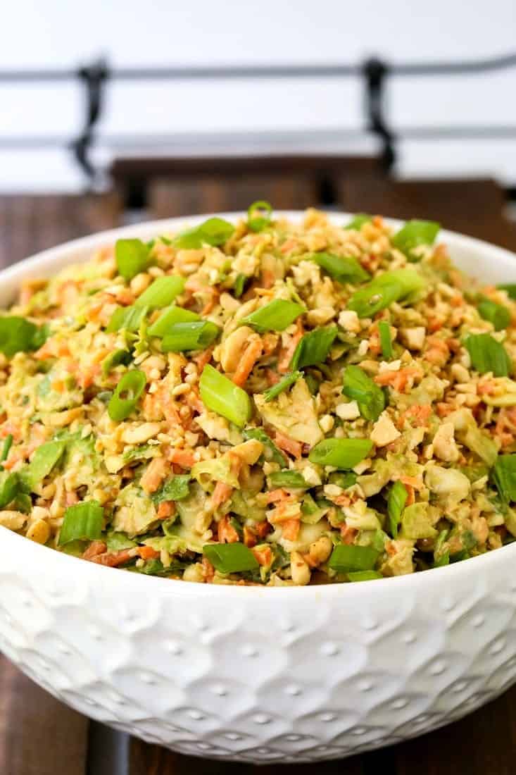 Thai Peanut Brussels Sprout Coleslaw in a white bowl on a serving tray