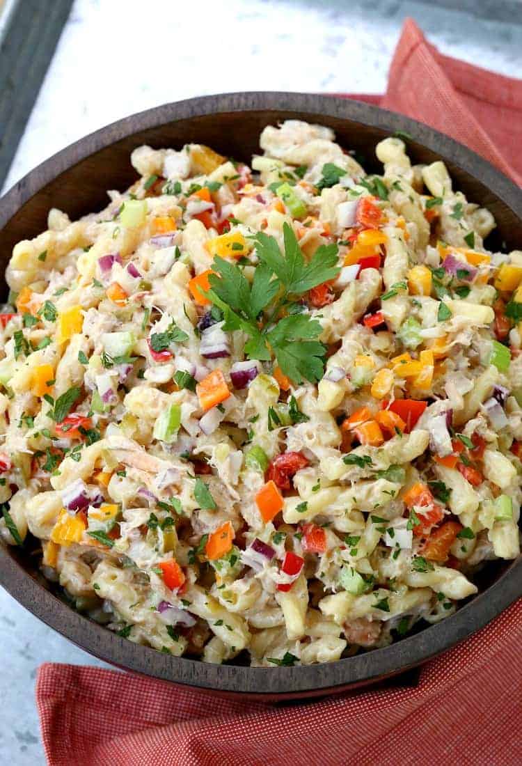 This Crab Pasta Salad is loaded with crab meat and tons of vegetables! All the flavors of a crab cake tossed with pasta and a tangy dressing! Crab cake pasta salad in a wood bowl with a red napkin