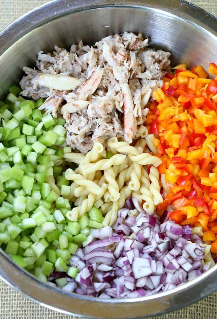 This Crab Pasta Salad is loaded with crab meat and tons of vegetables! All the flavors of a crab cake tossed with pasta and a tangy dressing! Crab Cake Pasta Salad ingredients in a metal bowl
