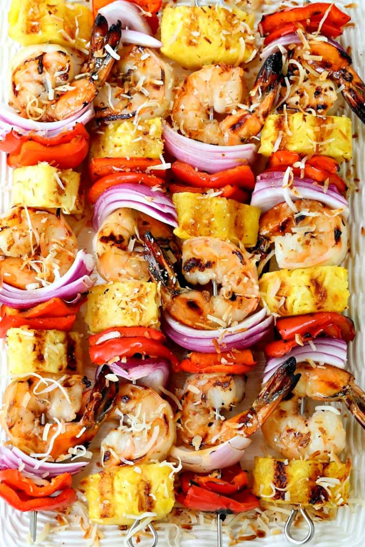 Piña Colada Shrimp Kabobs are the ultimate summer dinner! Juicy shrimp with a real piña colada flavor grilled with pineapple and vegetables. shrimp kabobs with pineapple on a platter