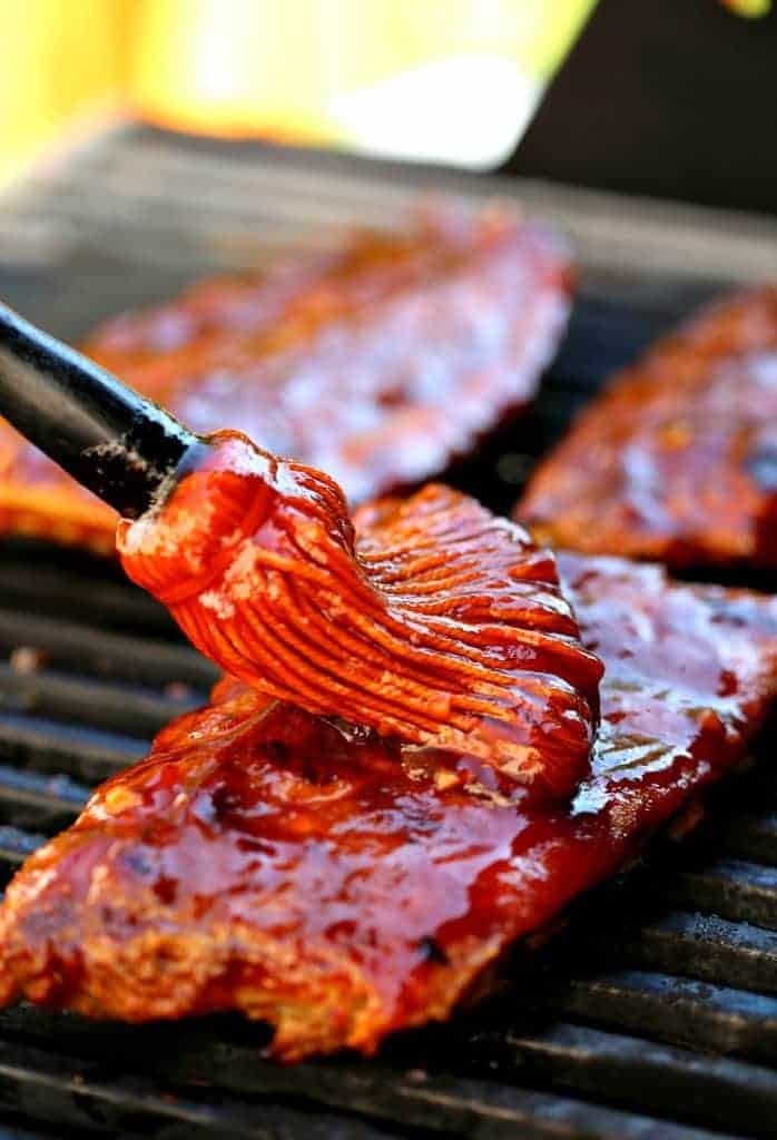 Sticky Root Beer BBQ Ribs on the grill, basting with root beer barbecue sauce