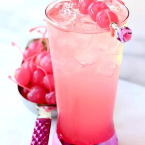 A pink shirley temple drink in a tall glass