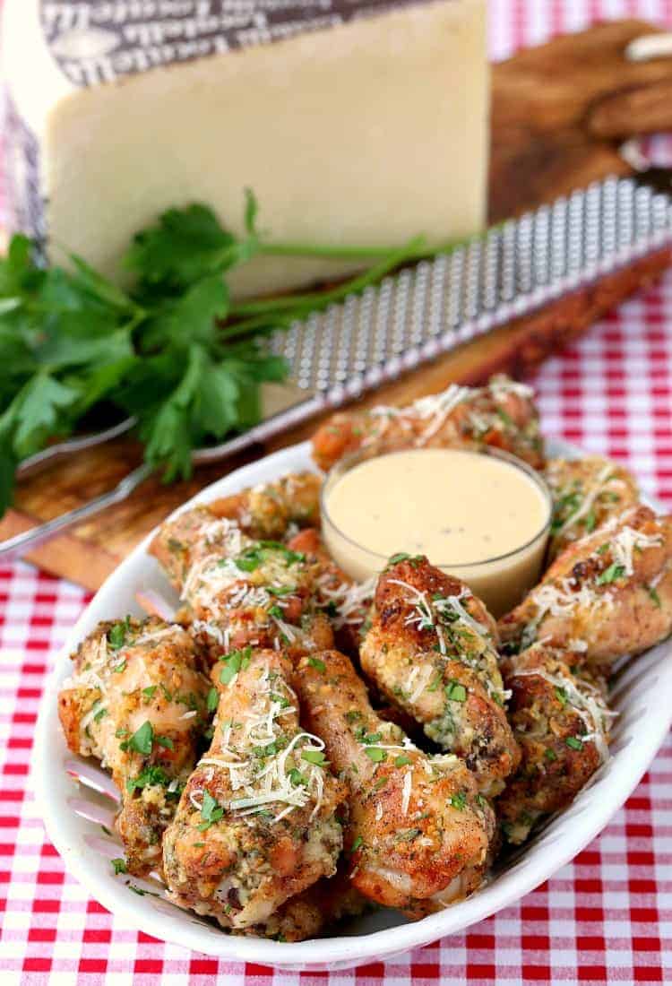 Baked Garlic Parmesan Chicken Wings on a platter with a parmesan cheese block and a grater in the background.