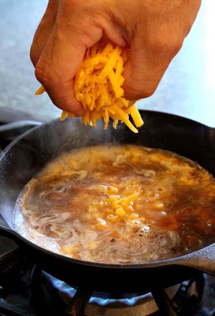 Adding cheese to a skillet to make queso