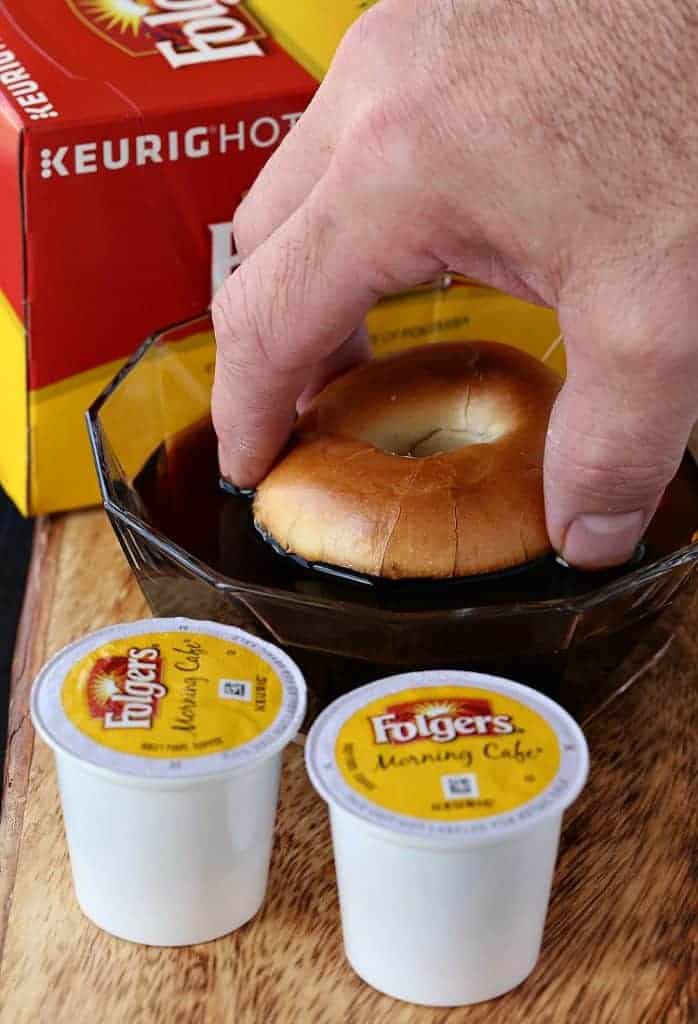 dipping toasted bagels into coffee for Tiramisu Cream Cheese Bagels