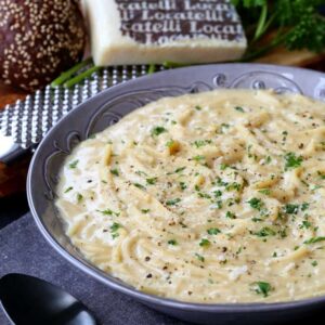 Cacio e Pepe Chowder in a bowl with bread and cheese