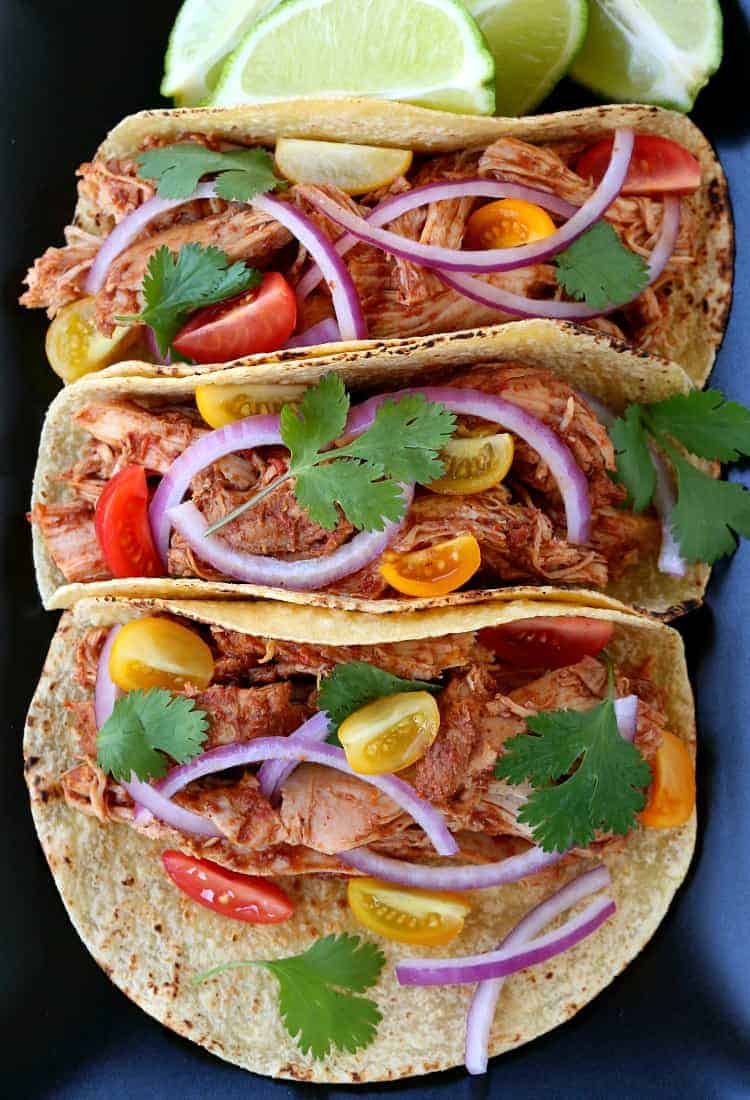 These Cinco de Mayo Recipes are going to make your party memorable. Fun dinner ideas that are totally on theme and so delicious! Three Slow Cooker Turkey mole tacos stacked on a black plate