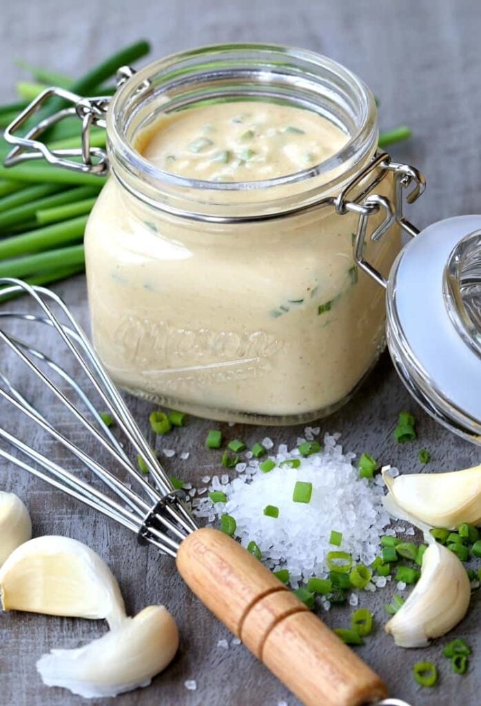 A jar of Awesome Sauce on a board with chives and salt