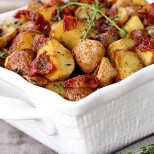 Crispy Oven Roasted Bacon Potatoes in a white dish with thyme