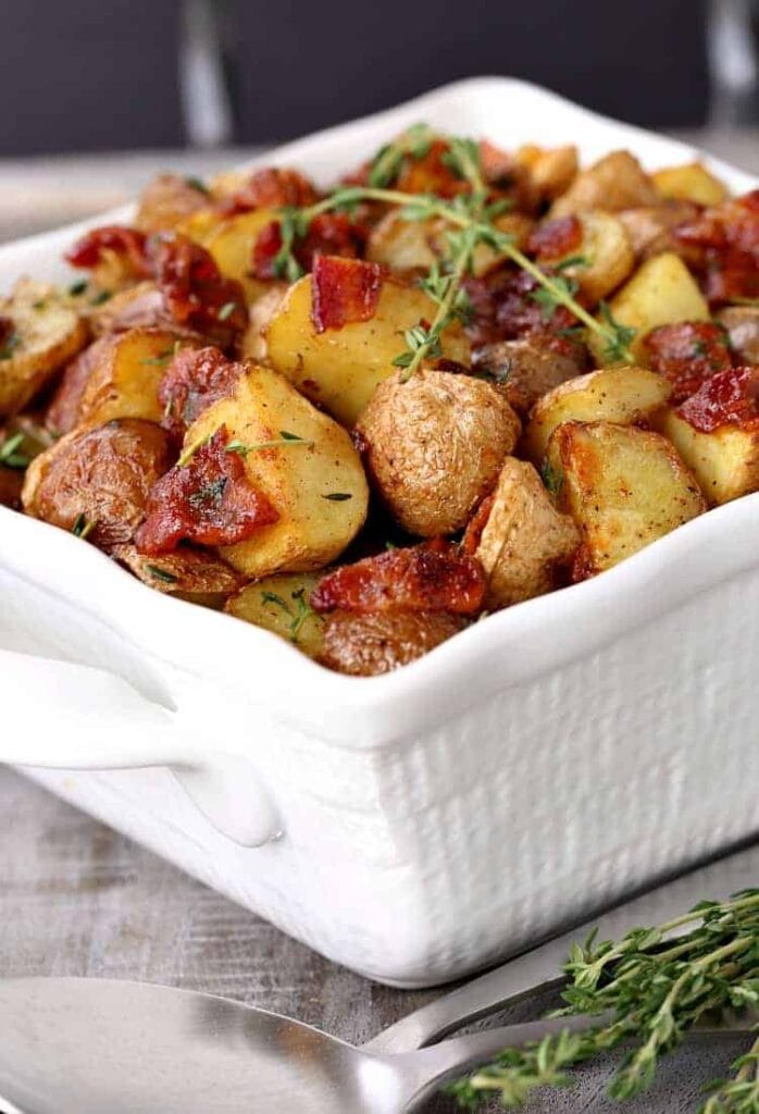 Crispy Oven Roasted Bacon Potatoes in a white dish with thyme