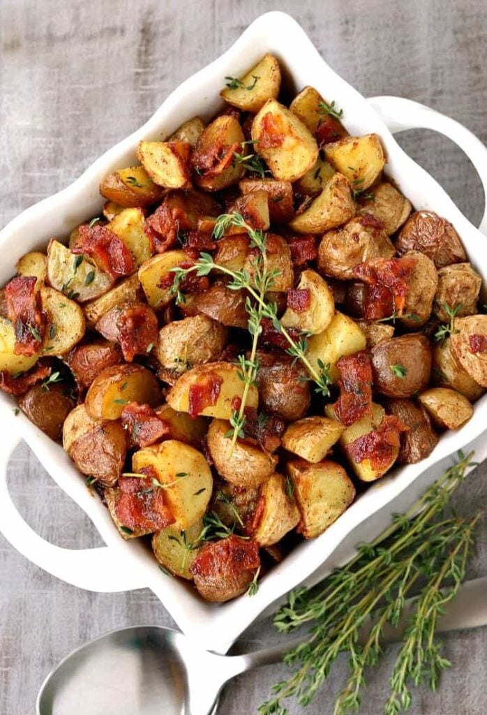 Crispy Oven Roasted Bacon Potatoes in a white bowl from the top view with spoons