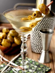 Grilled Dirty Martini in glass with shaker and olives and cocktail napkin