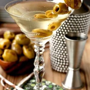 Grilled Dirty Martini in glass with shaker and olives and cocktail napkin