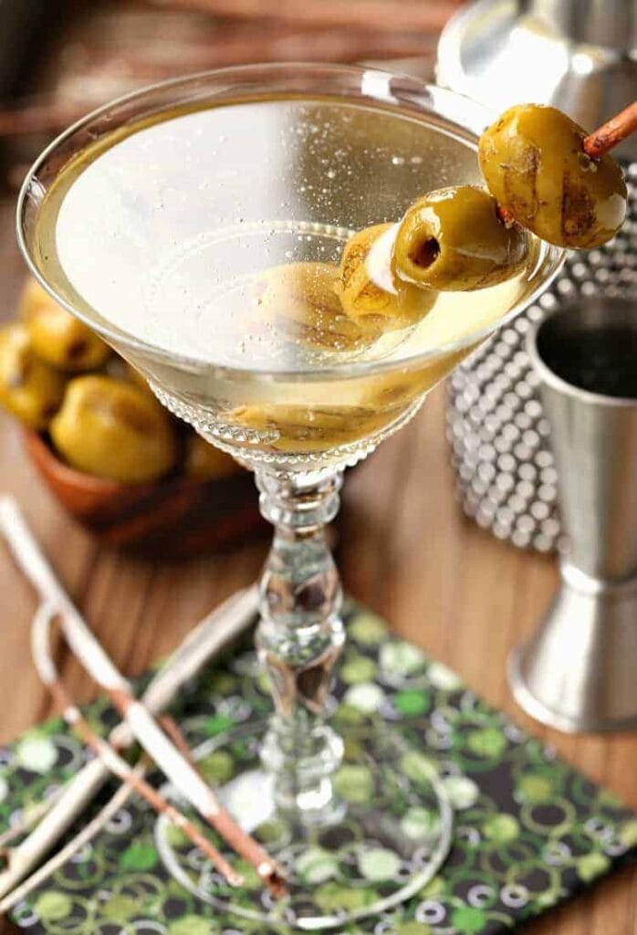 Grilled Dirty Martini in glass with shaker and olives