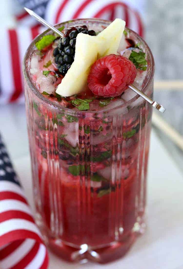 Try a Red White and Blue Mojito for your BBQ this weekend! These fun and festive mojito recipe is going to be a hit with the whole crowd! Red White and Blue Mojito with garnish from the top