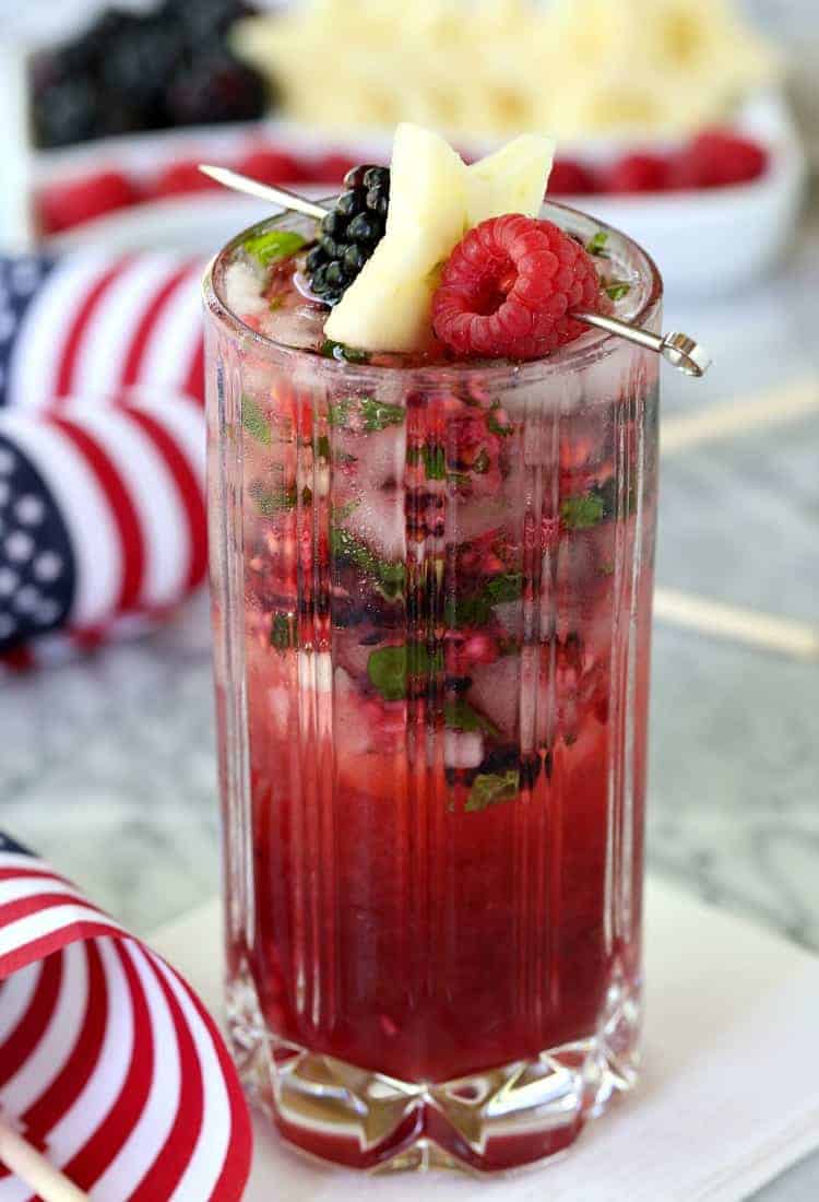 Try a Red White and Blue Mojito for your BBQ this weekend! These fun and festive mojito recipe is going to be a hit with the whole crowd! Red White and Blue Mojito with flags and garnish