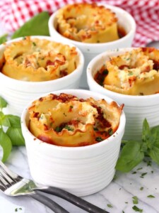Individual Lasagna Cups on a board with basil and forks