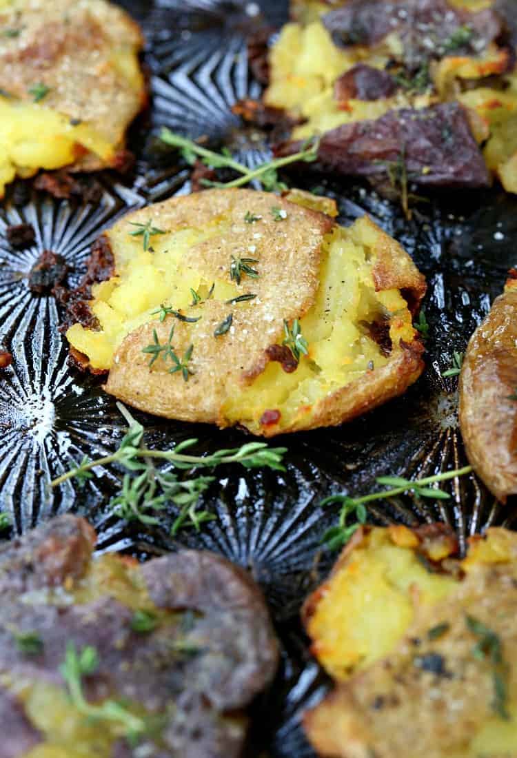 smashed potatoes on a black sheet pan