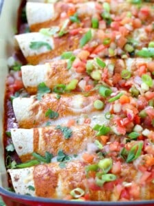Charred Corn Chicken and Poblano Enchiladas in a red baking dish with cheese