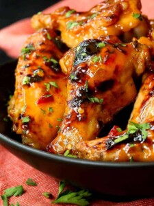 Slow Cooker Sweet Chili Chicken Wings close up in a black dish with a red towel