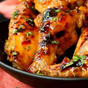 Slow Cooker Sweet Chili Chicken Wings close up in a black dish with a red towel