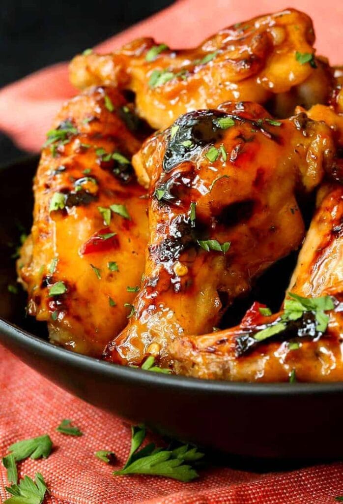 Slow Cooker Sweet Chili Chicken Wings close up in a black dish with a red towel