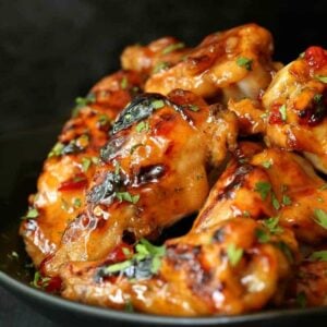 Slow Cooker Sweet Chili Chicken Wings in a black dish and black background