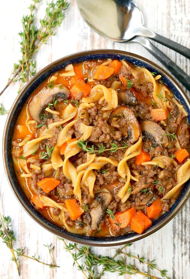 Beef Burgundy Mushroom Soup in blue bowl on a board with thyme from the top