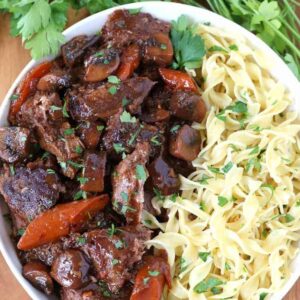 French Bistro Beef Stew in a bowl with noodles on a board