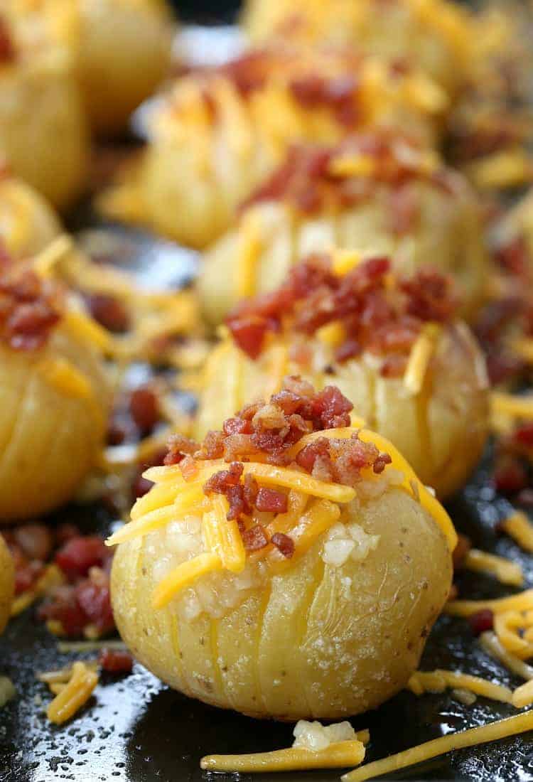 These mini loaded hasselback potatoes are full of gooey cheese and rich bacon, plus they're a quick and easy side dish to make A tray of mini loaded hasselback potatoes, topped with garlic, shredded cheese, and bacon bits, ready for the oven