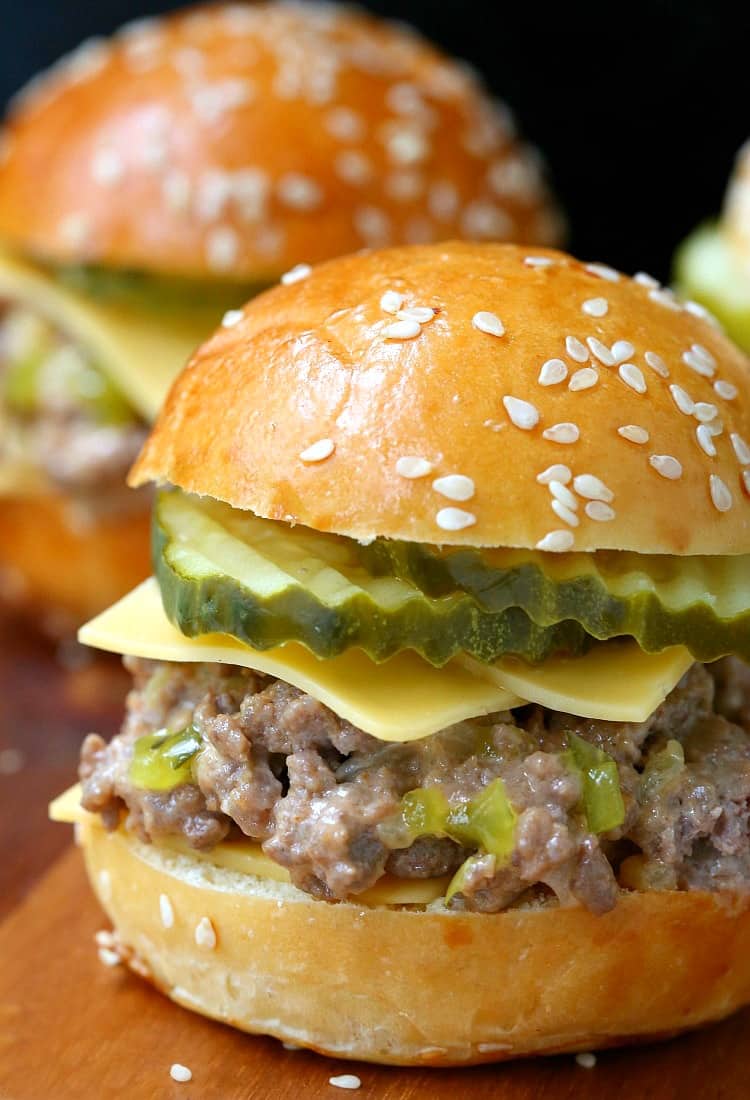 A ground beef slider with cheese and pickle slices 