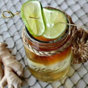 A Dark and Stormy drink in a mason cup with limes