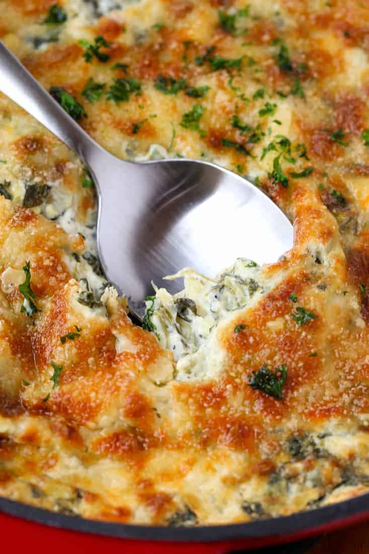 Spinach Artichoke Dip is a dip recipe topped with cheese with a creamy spinach and artichoke center