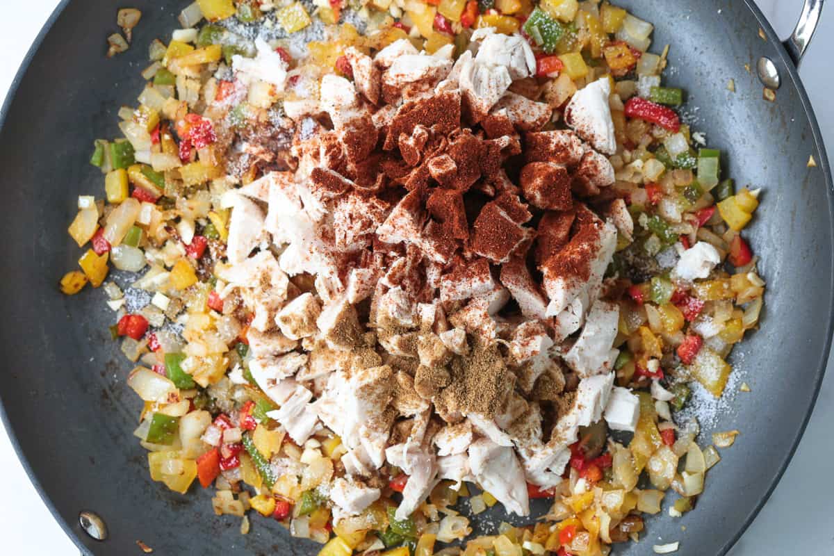 Chicken Fajita Rice is packed with charred vegetables, tender chicken and seasoned rice. Ideal for busy nights, ready in less than 30 minutes! seasoned chicken in a pan with peppers and onions