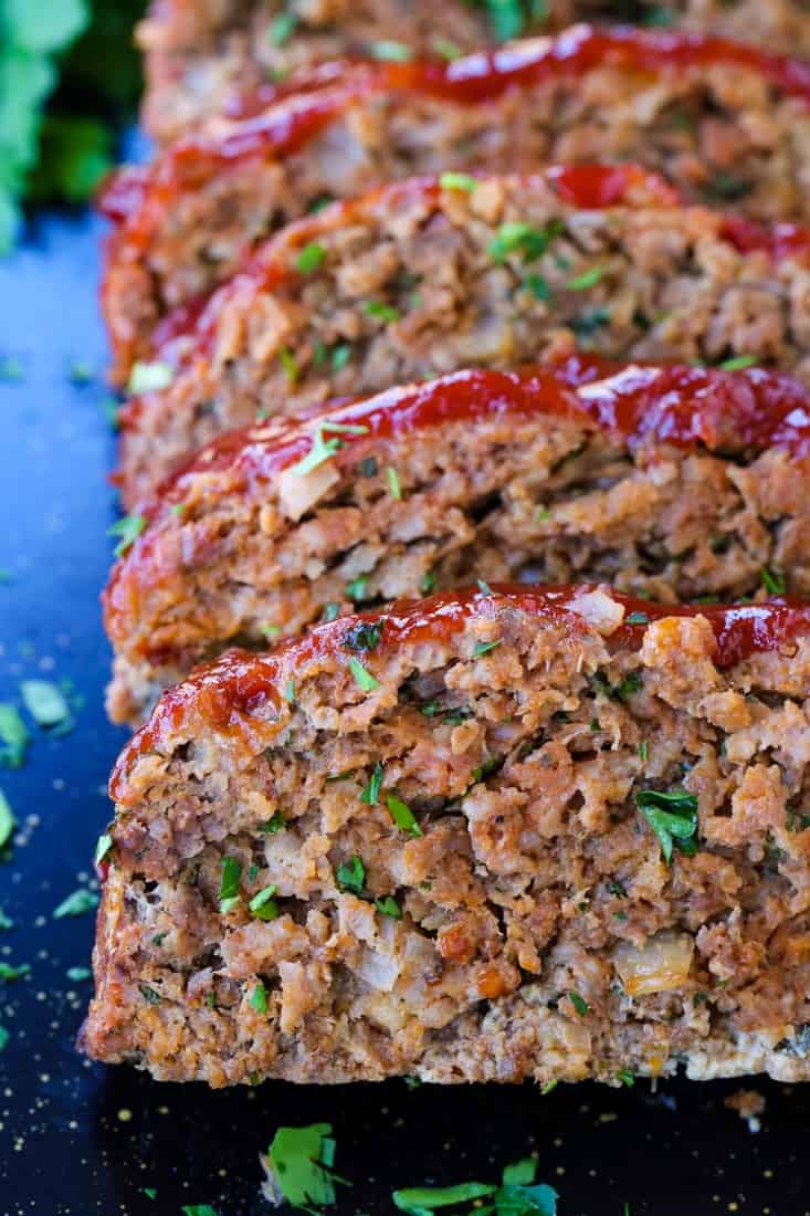 This Classic Meatloaf Recipe with ketchup glaze brings me back to my childhood! Tender, flavorful meatloaf recipe with a tomato glaze! Sliced meatloaf on a black serving platter