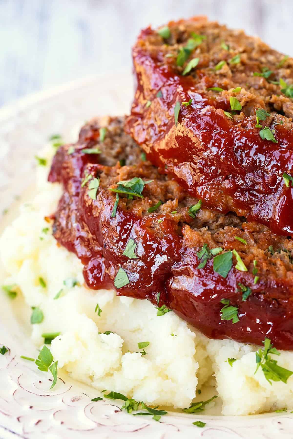 slices of glazed meatloaf on top of mashed potatoes