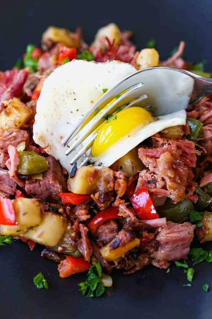 Corned Beef Hash recipe with fork cutting into fried egg