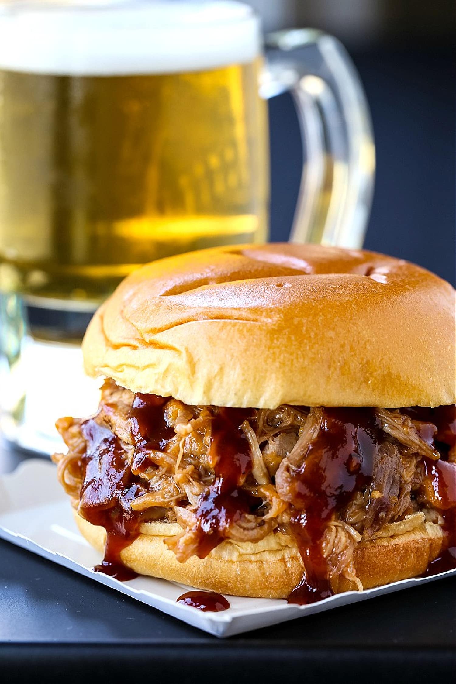 bbq pulled pork sandwich with beer in background