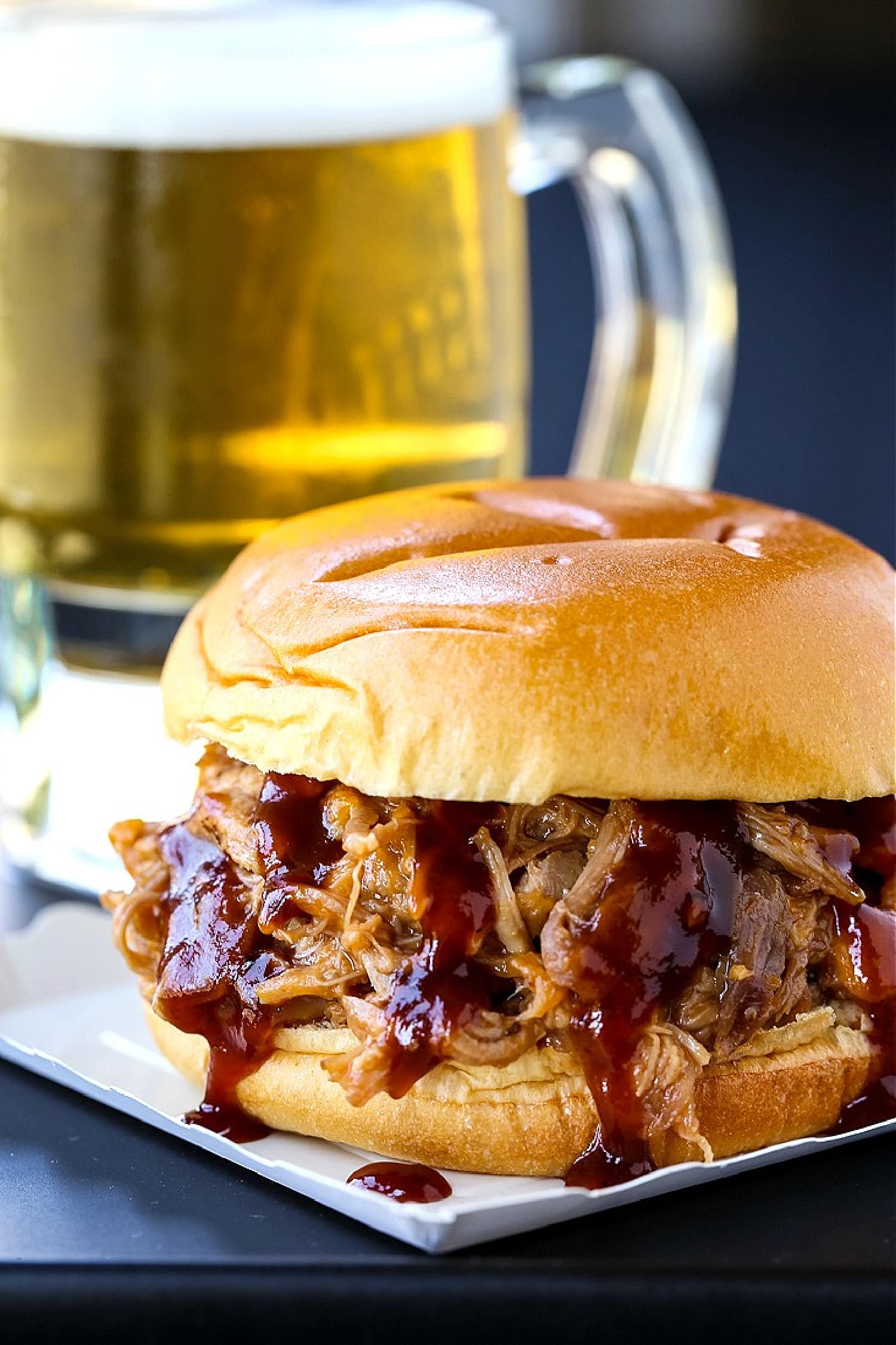 bbq pulled pork sandwich with beer in background