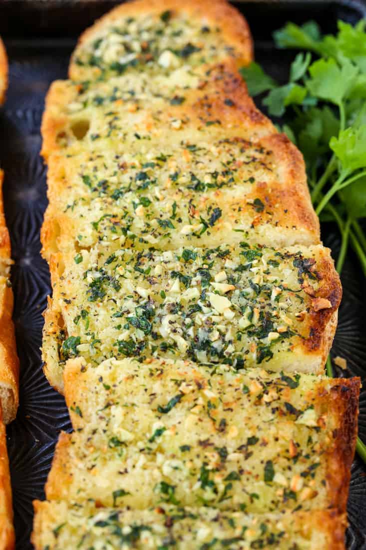 Garlic Bread sliced on a baking tray with parsley