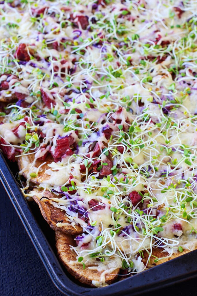 Irish Nachos with Corned Beef are perfect for St. Patrick's Day! Thin, crispy potatoes topped with corned beef and tons of cheddar cheese. Irish nachos topped with corned beef and cabbage