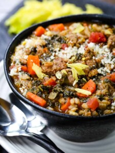 chicken sausage soup with spinach and farro in black bowl