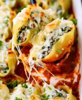 stuffed shells on a spoon over casserole dish