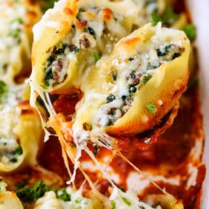 stuffed shells on a spoon over casserole dish