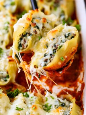 stuffed shells on a spoon over casserole dish