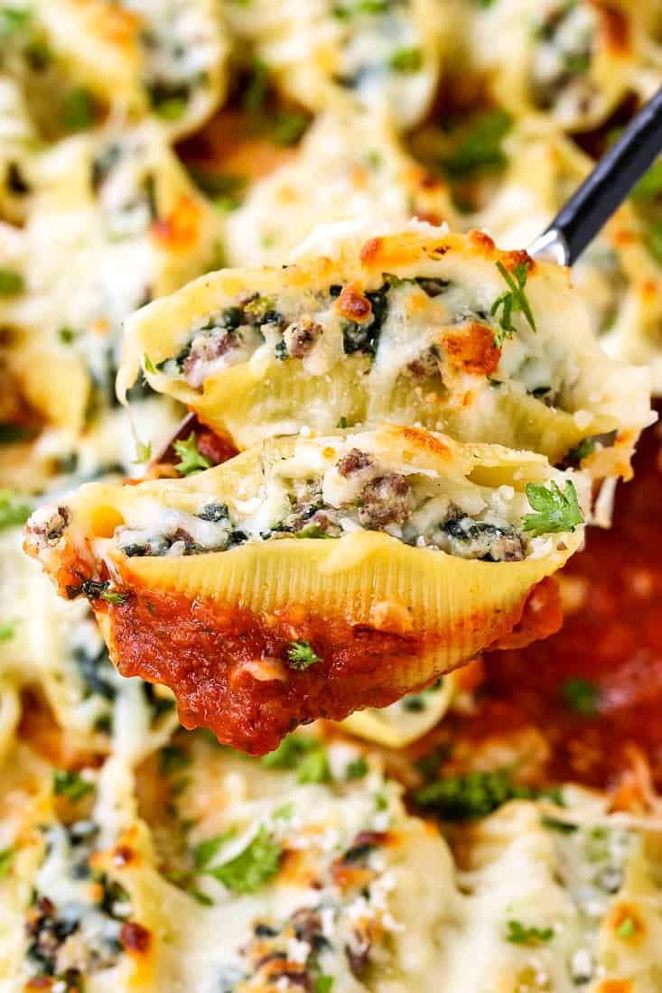 Two Beef Stuffed Shells on a spoon with some red sauce being shown off to the camera.