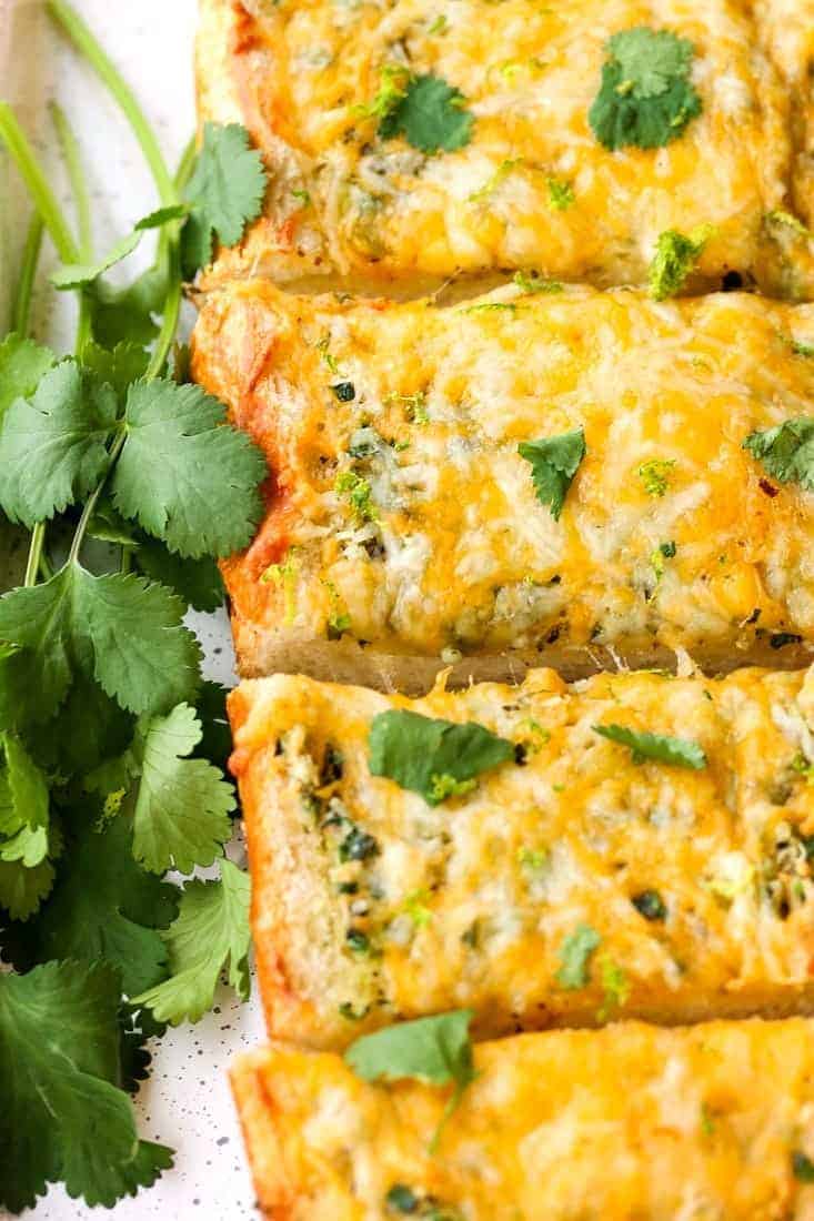 This Cheesy Mexican Garlic Bread is a fun side dish for everyday dinners, but also a super tasty appetizer for your next holiday or party! Cheesy Mexican Garlic Bread is a garlic bread recipe with a Mexican blend cheese melted on top
