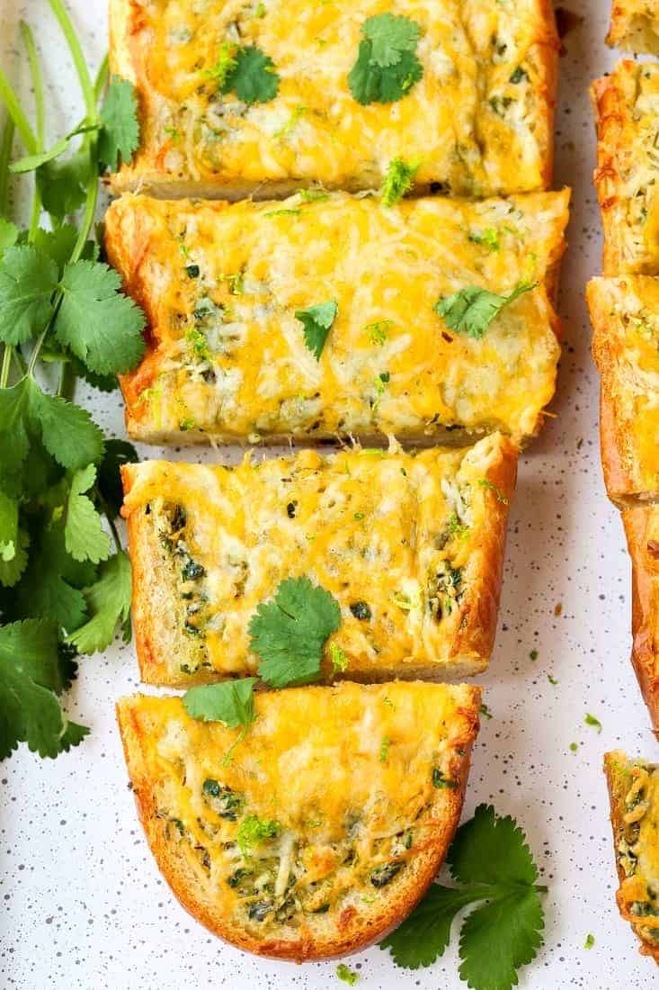 This Cheesy Mexican Garlic Bread is a fun side dish for everyday dinners, but also a super tasty appetizer for your next holiday or party! Cheesy Mexican Garlic Bread is a garlic bread recipe topped with cheese and cilantro